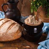 smalec w garmuszku obok chleb obsypany mąką, drewniana łyżka i pietruszka